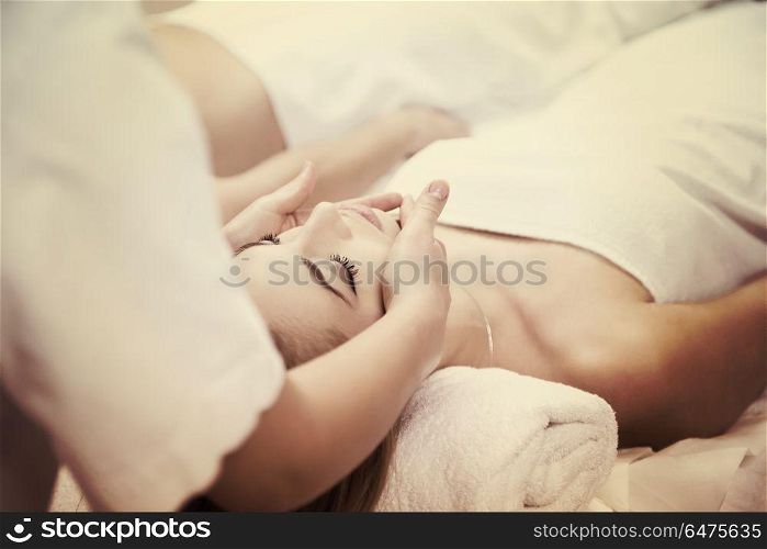 beautiful young woman getting face and head massage in spa and wellness salon. woman getting face and head massage in spa salon