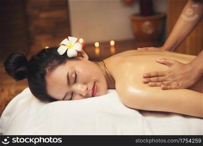 Beautiful young woman getting spa massage salon and white flower on her ear.