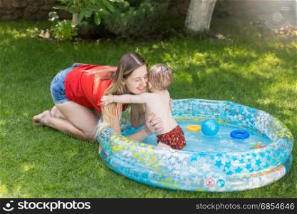 Beautiful young woman having fun with her baby boy in swimming pool