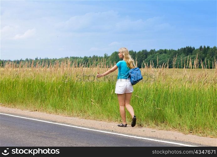 Beautiful young woman hitch hiking- in auto-stop &acute;votes&acute; on road