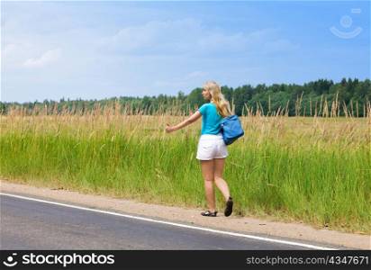 Beautiful young woman hitch hiking- in auto-stop &acute;votes&acute; on road