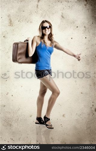 Beautiful young woman hitch hiking with old leather suitcase - grunge background aded in PS