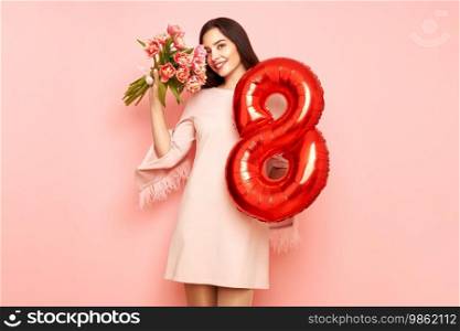 Beautiful young woman hold bouquet of tulips flowers and balloon number 8, rejoices spring holiday. Women’s Day on March 8th