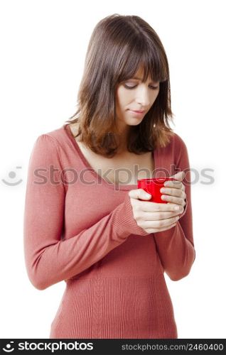 Beautiful young woman holding a cup of coffee, against a white wall