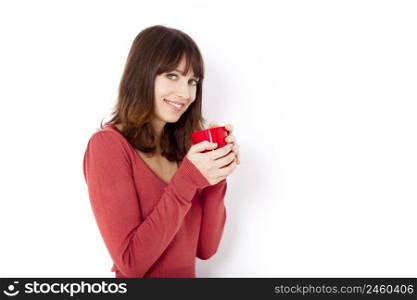 Beautiful young woman holding a cup of coffee, against a white wall
