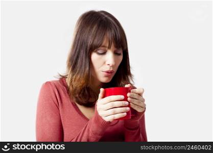 Beautiful young woman holding a cup of coffee, isolated on a gray background