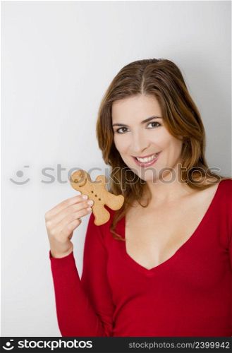 Beautiful young woman holding a gingerbread cookie