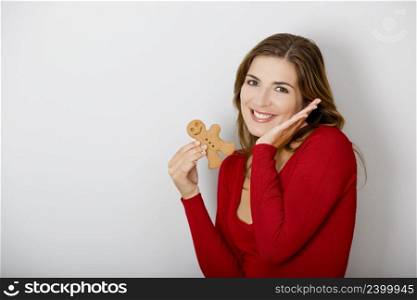 Beautiful young woman holding a gingerbread man cookie