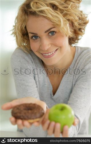 beautiful young woman holding an apple and a donut