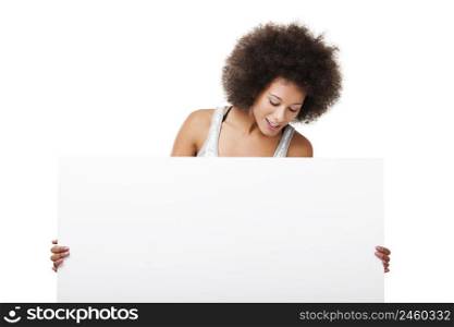 Beautiful young woman holding and looking to a white billboard with copy space, isolated on white