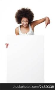 Beautiful young woman holding and pointing to a white billboard with copy space, isolated on white