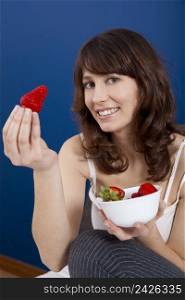 Beautiful young woman holding and showing a big and fresh strawberry