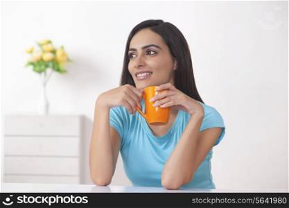 Beautiful young woman holding coffee cup at home