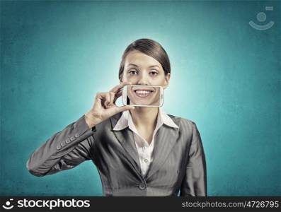 Beautiful young woman holding mobile phone against her mouth and smiling . Mobile phone demonstration