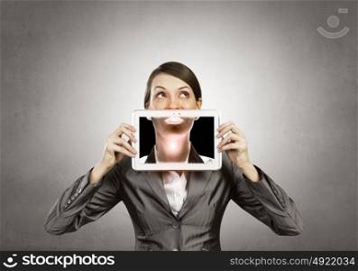 Beautiful young woman holding tablet against her mouth and smiling . Woman with tablet
