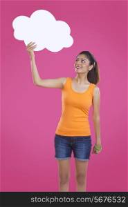 Beautiful young woman holding thought bubble over pink background