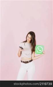 beautiful young woman holding whatsapp icon using mobile phone