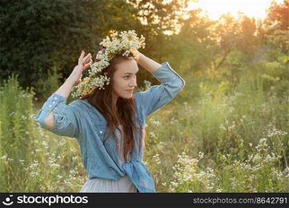 Beautiful young woman holding wildflowers bouquet and  walking in flower field on sunset.