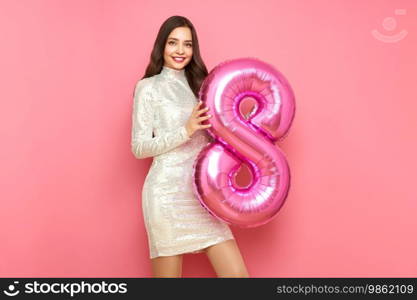 Beautiful young woman in a festive dress hold balloon number 8, rejoices spring holiday. Women’s Day on March 8th