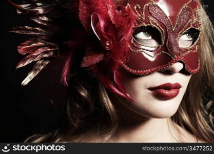 Beautiful young woman in a red mysterious venetian mask