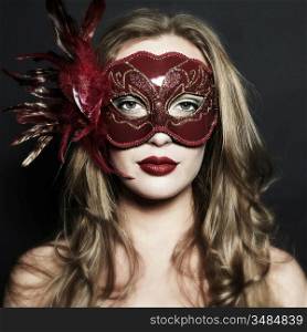 Beautiful young woman in a red mysterious venetian mask