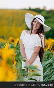 beautiful young woman in a white dress and hat on a field of sunflowers , smiling a beautiful smile,cheerful girl,style, lifestyle , ideal for advertising and photo sun shines bright and juicy. selective focus.. beautiful young woman in a white dress and hat on a field of sunflowers , smiling a beautiful smile,cheerful girl,style, lifestyle , ideal for advertising selective focus