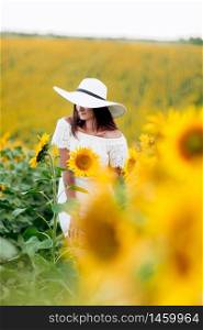 beautiful young woman in a white dress and hat on a field of sunflowers , smiling a beautiful smile,cheerful girl,style, lifestyle , ideal for advertising and photo sun shines bright and juicy. selective focus.. beautiful young woman in a white dress and hat on a field of sunflowers , smiling a beautiful smile,cheerful girl,style, lifestyle , ideal for advertising. selective focus