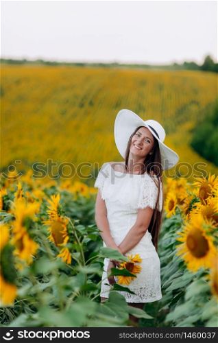 beautiful young woman in a white dress and hat on a field of sunflowers , smiling a beautiful smile,cheerful girl,style, lifestyle , ideal for advertising and photo sun shines bright and juicy. selective focus.. beautiful young woman in a white dress and hat on a field of sunflowers , smiling a beautiful smile,cheerful girl,style, lifestyle , ideal for advertising. selective focus