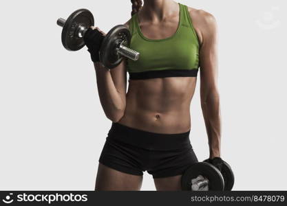 Beautiful young woman in a workout gear lifting dumbbells