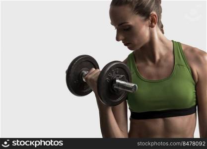 Beautiful young woman in a workout gear lifting dumbbells