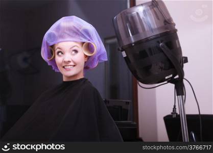 Beautiful young woman in beauty salon. Blond girl with hair curlers rollers. Modern equipment by hairdresser. Hairstyle.
