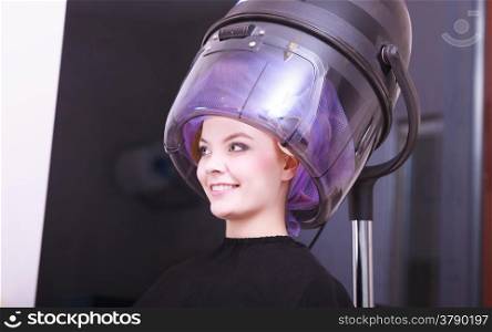 Beautiful young woman in beauty salon. Blond girl with hair curlers rollers. Modern equipment by hairdresser. Hairstyle.