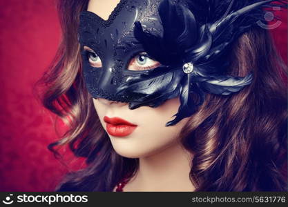 Beautiful young woman in black mysterious Venetian mask. Fashion photo