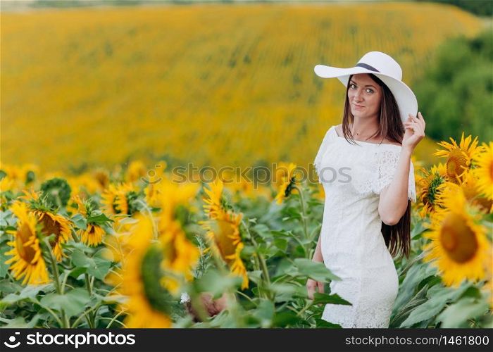 beautiful young woman in blooming sunflowers field in summer. Stylish girl with long hair in white dress and hat. summer holiday.. beautiful young woman in blooming sunflowers field in summer. Stylish girl with long hair in white dress and hat. summer holiday