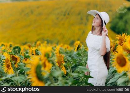 beautiful young woman in blooming sunflowers field in summer. Stylish girl with long hair in white dress and hat. summer holiday.. beautiful young woman in blooming sunflowers field in summer. Stylish girl with long hair in white dress and hat. summer holiday