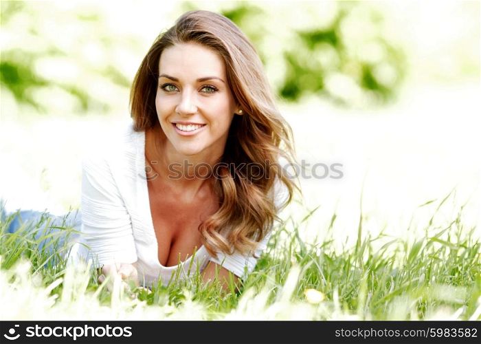 beautiful young woman in blue dress lying on grass. young woman in blue dress lying on grass