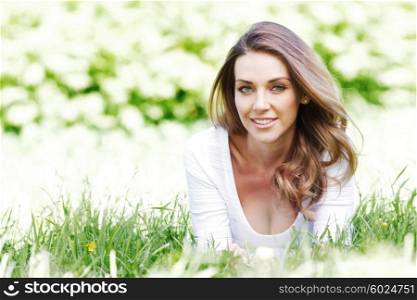 beautiful young woman in blue dress lying on grass. young woman in blue dress lying on grass