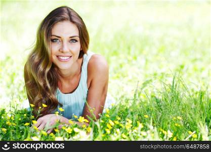 beautiful young woman in blue dress lying on grass. young woman in blue dress lying on grass. young woman in blue dress lying on grass