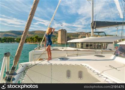 beautiful young woman in casual wear standing on a yacht fore at Trogir marina, Croatia, Europe. beautiful young woman in casual wear standing on a yacht fore at Trogir marina, Croatia