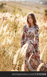 beautiful young woman in dress in field at sunset. stylish romantic girl with long hair having fun outdoors. beautiful young woman in dress in field at sunset. stylish romantic girl with long hair having fun outdoors.