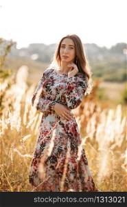 beautiful young woman in dress in field at sunset. stylish romantic girl with long hair having fun outdoors. beautiful young woman in dress in field at sunset. stylish romantic girl with long hair having fun outdoors.