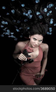 beautiful young woman in elegant red dress with a rose and petals on hair