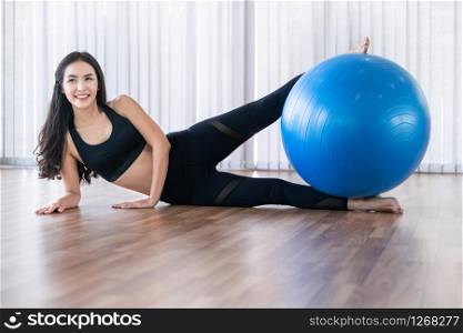 Beautiful young woman in fitness center doing pilates exercise with fitness ball. Healthy lifestyle concept.