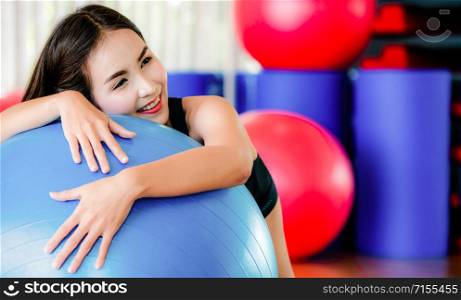 Beautiful young woman in fitness center doing pilates exercise with fitness ball. Healthy lifestyle concept.