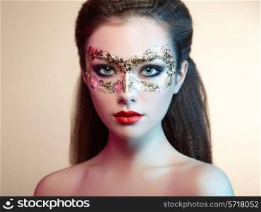 Beautiful young woman in gold mysterious mask. Perfect makeup. Fashion photo