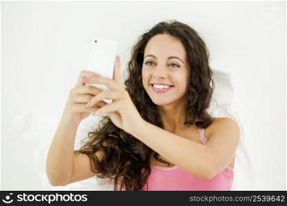Beautiful young woman in lying on the bed and making a selfie