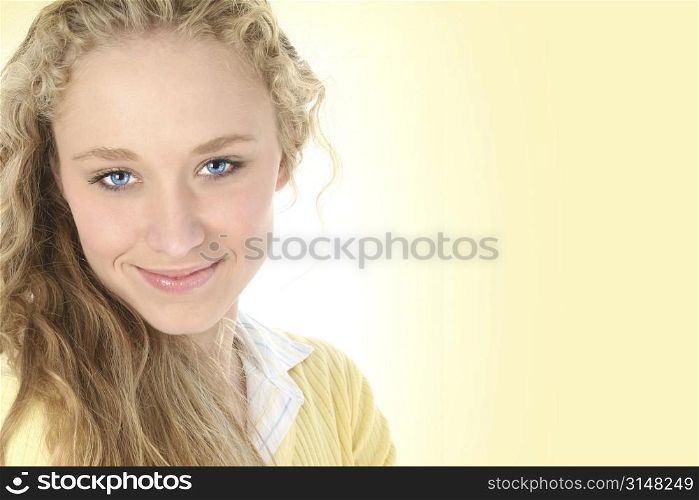 Beautiful young woman in pale yellow. Long curly blonde hair and blue eyes.