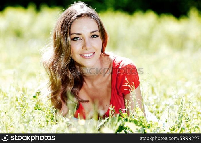 beautiful young woman in red dress lying on grass. young woman in red dress lying on grass