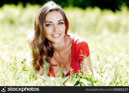 beautiful young woman in red dress lying on grass. young woman in red dress lying on grass