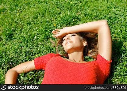 beautiful young woman in red dress lying on grass. young woman in red dress lying on grass. young woman in red dress lying on grass